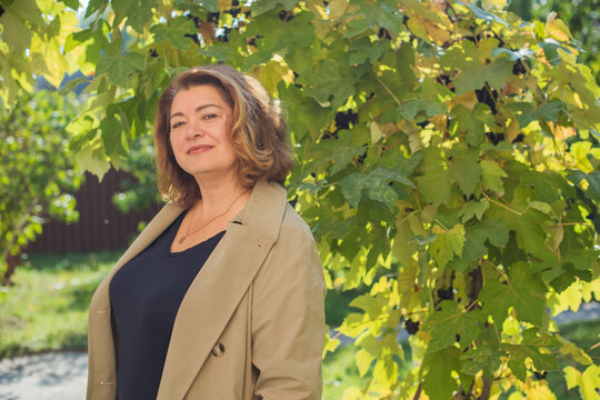 Happy plus size mature woman in her 50s smiling outdoors in an elegant classic outfit. Positive lifestyle portrait celebrating mature beauty, confidence, happiness, self acceptance and an active 55s