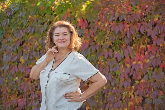 Happy plus size mature woman in her 50s smiling outdoors in an elegant classic outfit. Positive lifestyle portrait celebrating mature beauty, confidence, happiness, self acceptance and an active 55s