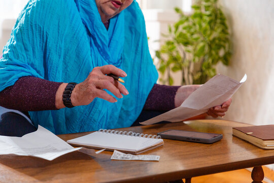 Senior Caucasian woman studying finance online while managing bills. Modern learning and need. Concept of financial hardship. Close up