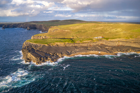 Aerial view of  Kilkee Cliffs and rugged coastline in County Clare, Ireland, during a golden evening light.