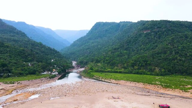 Dry riverbed surrounded by border hills and indigenous village near Bangladesh India border - aerial.