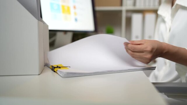 Business professional organizing stacks of documents and reviewing office paperwork for efficient administration and record management.