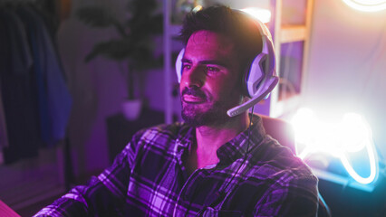 Man wearing headset holds controller with hand on joystick and leans toward screen in studio  concentration gaming. © Krakenimages.com