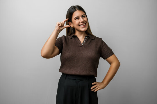Woman hispanic beautiful young in casual clothes, studio portrait of a confident woman gesturing with hand and fingers showing a small size sign, finger measure concept