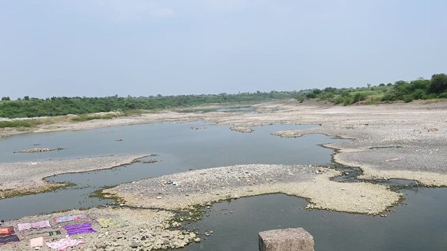 completely dry rocky riverbed winding through a parched rural landscape. This footage highlights severe drought, water scarcity, and the impact of climate change.