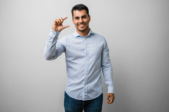Man young casual clothes hand size small sign concept finger gesturing measure fingers confident studio portrait, smiling bearded male showing tiny pinch gesture and relaxed pose