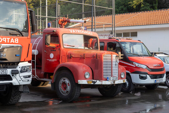 June 26, 2026, Petrovac, Montenegro, Vintage red fire truck parked next to modern fire vehicles in a fire station yard with a building