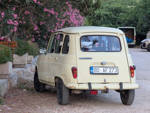 June 28, 2026, Petrovac, Montenegro, Vintage Renault 4 parked on a gravel road surrounded by blooming pink flowers and green foliage in a quiet area