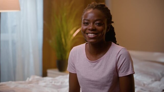 Happy smiling African American business woman looking at camera working on laptop in bedroom at night female businesswoman freelancer using computer on bed remote work from home bedtime evening indoor