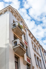 Historic Apartment Facade with Weathered Balconies Beneath a Cloudy Blue Sky © STOATPHOTO