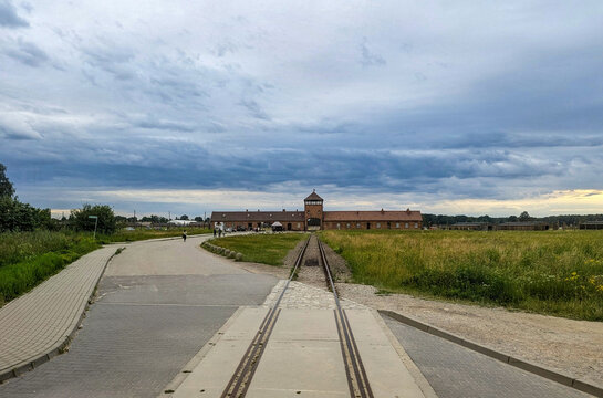 July 7, 2026, Oswiecim, Poland, View of the Auschwitz-Birkenau Memorial with Railway Tracks and Curved Path Under Overcast Sky in Poland