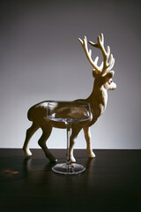 Empty champagne coupe glass and festive glitter reindeer figurine on dark table for Christmas and New Year celebration © ShapeImages