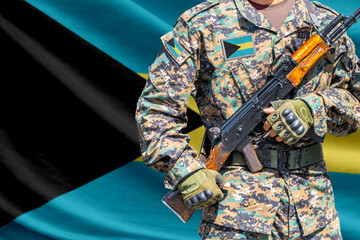 Fototapeta premium Bahamas flag with soldier in military uniform holding assault rifle in front of it