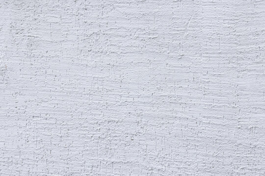 Flat white wall exterior during daytime - dragged plaster pattern.. The plain surface creates a neutral backdrop suitable for various uses.