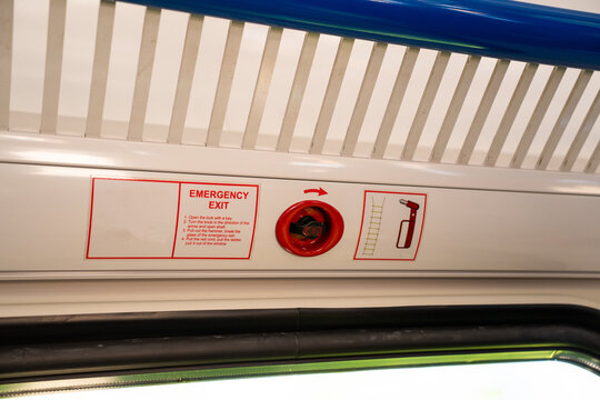 Emergency exit instructions sticker with red lock and hammer pictogram inside passenger train
