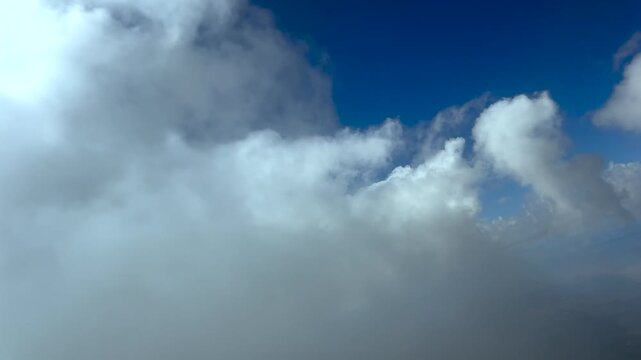 An immersive cockpit view captured in a right turn through ethereal white fluffy clouds in a blue sky. 4K aerial shot.