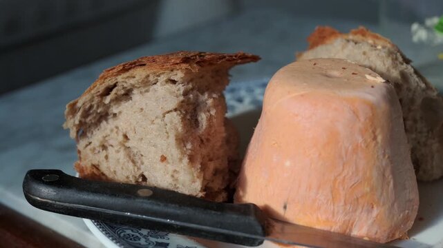 Close up shot of a traditional asturian cheese, afuega'l pitu, served on a plate with crusty bread and a knife