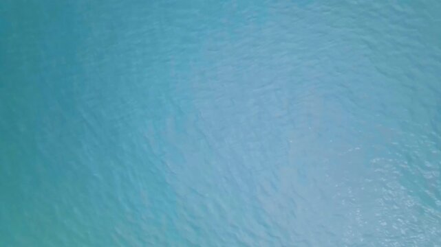Calming aerial view of turquoise ocean water moving gently with small relaxing ripples creating a beautiful abstract texture