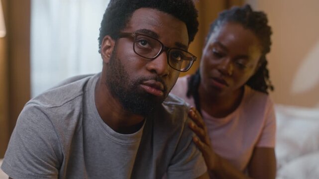 Sad African American depressed husband sitting on bed wife comforting calming family relationship crisis support couple pain worried suffering breakdown impotence health at home bedroom evening night