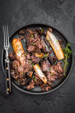 Braised beef ribs with shredded texture and bones served in skillet. Slow cooked beef short ribs with plate and back ribs look.