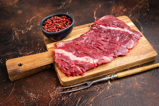 aw bavette flap steak also known as arrachera vacio cut placed on wooden board. Fresh beef with visible grain on dark rustic background with copyspace.
