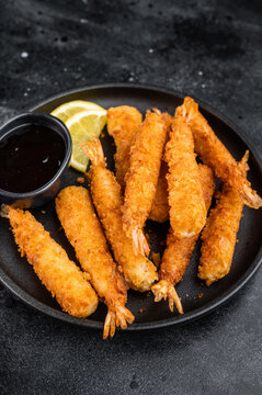 Panko fried prawns or ebi fry arranged on plate with sauce bowl and citrus wedges, crunchy deep fried seafood snack shot from above with copy space.