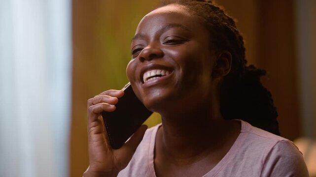 Happy African American woman answering mobile phone call close up portrait home bedroom late evening cheerful female girl smartphone conversation speaking cellphone friendly talking telephone indoor