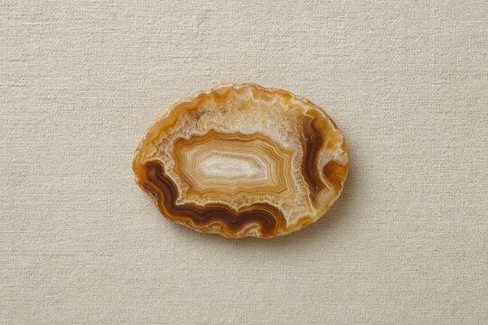 Polished banded agate slice on beige linen