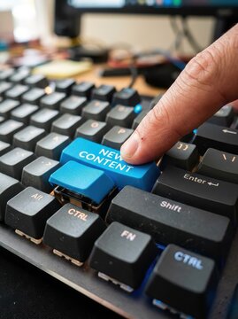 Close-up of a Finger Pressing a Blue New Content Key on a Mechanical Computer Keyboard for Digital Marketing and Blogging