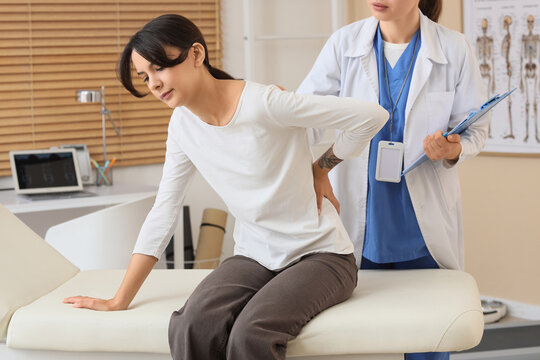 Back pain and physical therapy, patient consulting with doctor about chronic spinal injury and musculoskeletal health in a medical clinic office