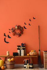Fototapeta premium Halloween celebration and autumn holiday decor, festive gift boxes with pumpkins and fall wreath on wooden bench against orange wall with paper bats