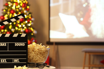 Fototapeta premium Christmas movie night and holiday entertainment, film clapperboard with popcorn and 3d glasses in front of a projector screen and decorated tree