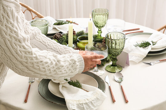 Christmas dinner preparation, woman setting festive table with green glassware and candles for holiday celebration and winter home hospitality