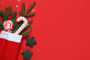 Fototapeta premium Christmas celebration and holiday spirit, festive stocking with candy canes and pine branches on a red background with copy space for seasonal greeting