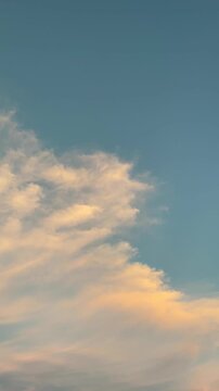 Soft clouds drifting in a blue sky at sunset vertical video