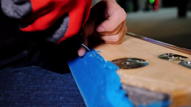 Close-up skilled hands carefully removing staples from billiard table fabric.