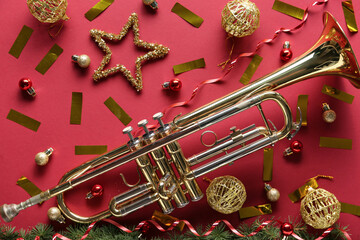 Golden brass trumpet with christmas ornaments and confetti on red background for holiday music celebration © Pixel-Shot