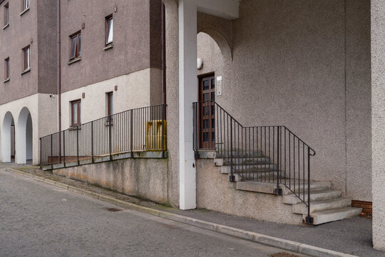 Concrete stairs and a metal disability access ramp providing entry to residential flats located on a quiet street in Nairn, Highlands, Scotland