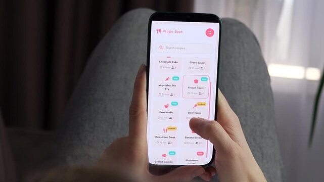 Person browses recipes on a smartphone, comparing dishes, cooking times and difficulty levels as mobile meal planning makes everyday home cooking faster and more convenient.