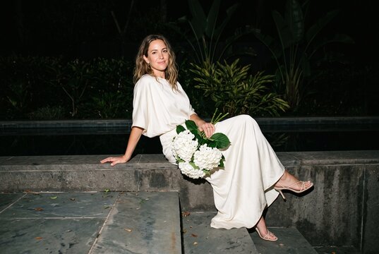 Elegant Woman Seated with White Bouquet in Night Garden