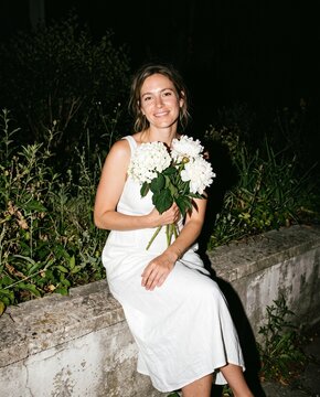 Elegant Woman in White Dress Holding Flowers at Night