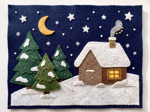 Handmade felt craft illustration of a snowy winter cabin with pine trees, crescent moon and stars, stitched wool felt