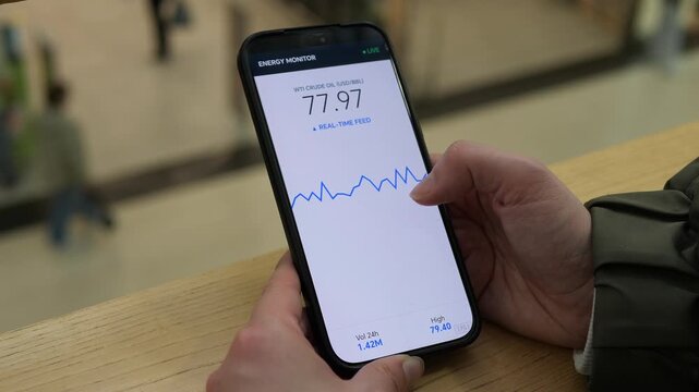 Person monitors live crude oil prices on a smartphone, tracking market fluctuations and energy trends as commodity volatility influences inflation, transport and the global economy.