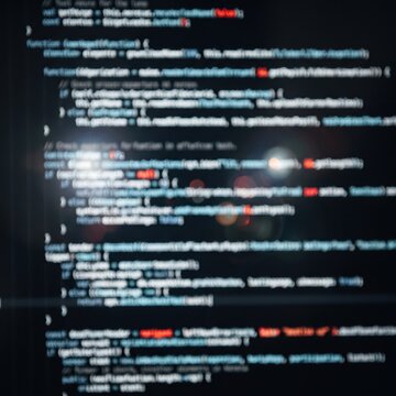 Blurred white code lines on a black background, abstract programming concept. Horizontal strips of out-of-focus text resemble glowing source code with a few red accents, arranged in a left-aligned