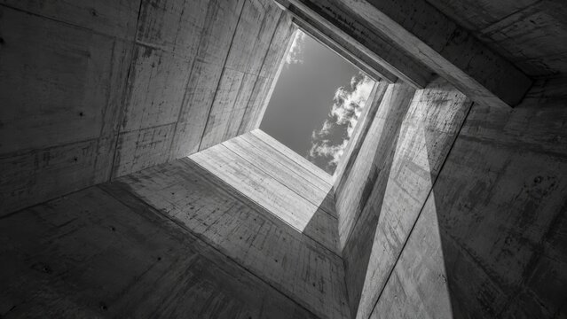 Modern architectural concrete structure with a sky view from within a deep square opening