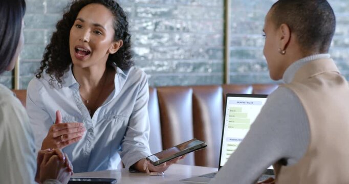 Diverse women in nook watching Asian presenting tablet, pointing at laptop chart and comparing data