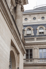 Classical Parisian building facade with balustrade, arched windows and stone columns © Alina Mir