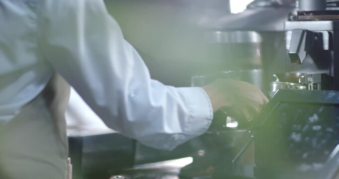 Barista is pressing grinder switch and dosing coffee into portafilter at cafe counter for espresso