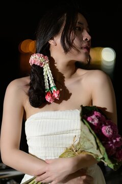 Young woman holding bouquet of flowers during outdoor evening at night