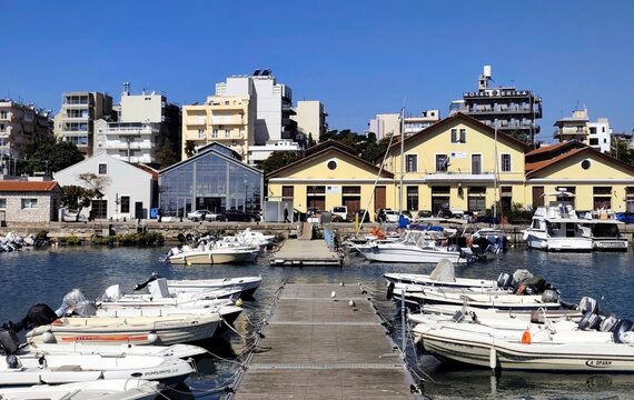 Photo of Alexandroupoli port in northeastern Greece, featuring fishing boats along its wooden pier and historic yellow railway warehouses dating to around 1870,reflecting the city's maritime heritage.